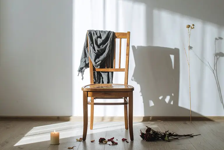 Silla vacía con prenda y flores marchitas en homenaje a un desaparecido, símbolo del duelo por desaparición forzada en México.