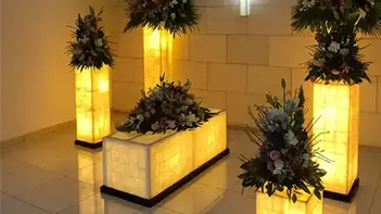 acompañamiento en el duelo - Sala de velación iluminada con arreglos florales y cruz en la pared